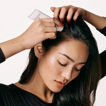 Kobieta aplikująca na skóre głowy serum Olaplex 0.5 Longevity